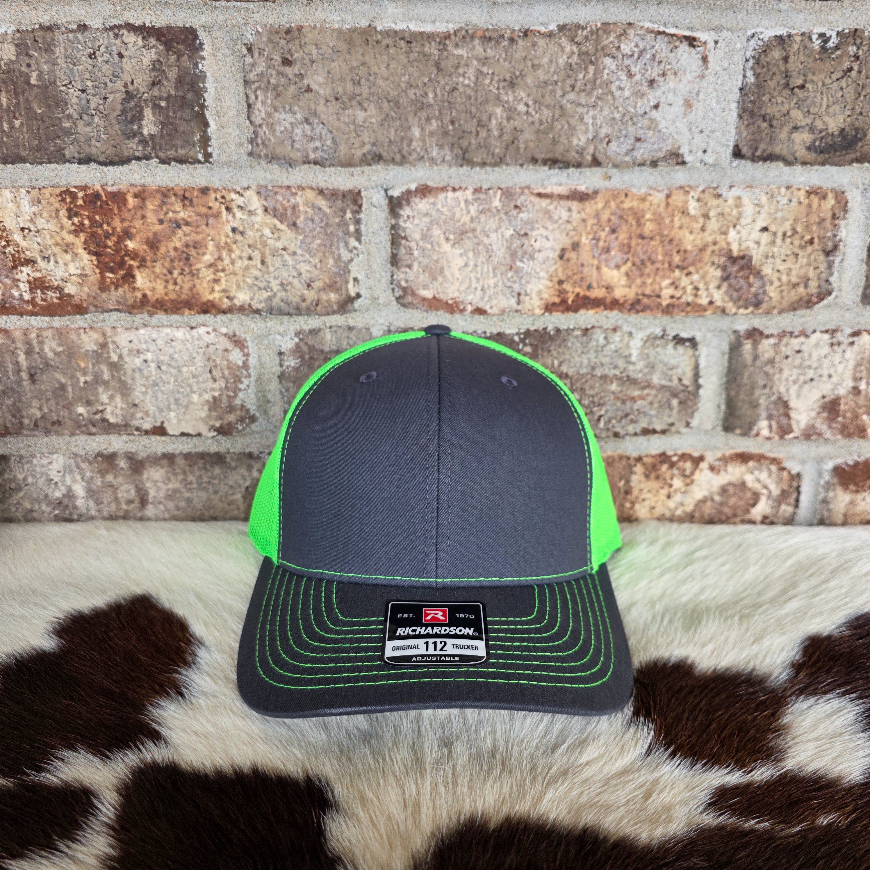 Black and green cap on a cowhide rug with a brick wall background