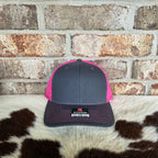 Gray and pink cap with Richardson logo on a cowhide rug against a brick wall.