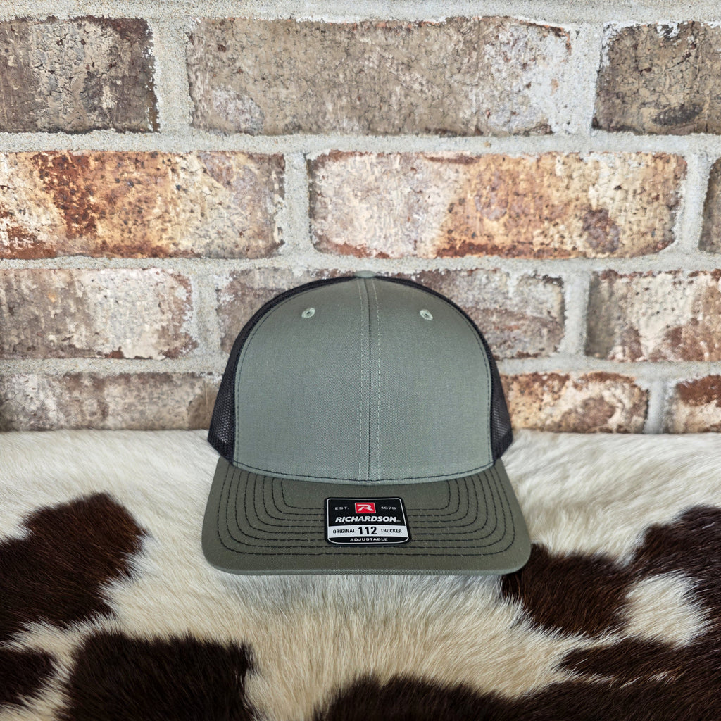 Gray cap with a logo on a cowhide rug against a brick wall