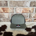 Gray cap with a logo on a cowhide rug against a brick wall